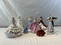 Group shot of all eight figurines in white gowns on table