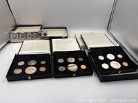 Overview of four 1967 Canadian Mint Centennial coin sets: three black leather boxes and one plastic proof case