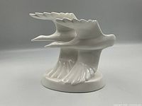 Front view of the Royal Doulton "Going Home" figurine showing two white geese in flight with wings extended, standing on an oval base.