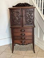 Full front view of hand carved wood cabinet on stand