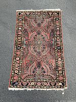 Full view of the handwoven area rug on asphalt, showing overall design and colors.