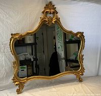 Front view of mirror showing full ornate gilt carved frame and reflective glass.
