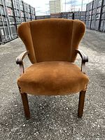 Front view of the brown velvet Mid Century Modern arm chair showing wear on upholstery and wooden legs.