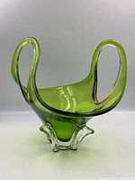 Front view of Mid Century Modern green art glass bowl with clear base and stretched form.