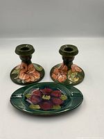 Front view of the pair of Moorcroft candlestick holders and oval tray, showing the floral motifs and glazing details.