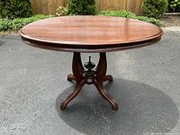 Front view of the oval wooden breakfast table outdoors showing table top and base.