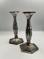 Pair of glass candlesticks shown side-by-side, highlighting the sterling silver overlay design on twisted bodies and hexagonal bases.