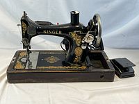 Side view of the Singer sewing machine mounted on a wooden base with foot pedal next to it.