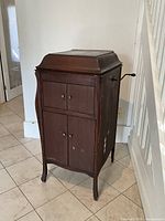 Front view of closed wooden cabinet gramophone showing curved sides and front doors
