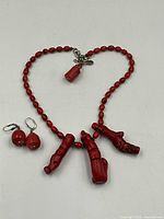 Full view of red coral necklace with three large branch coral pendants and matching earrings on white background.