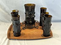 Set of 6 amber glass highball drinking glasses in wrought iron Brutalist cages on a teak tray with matching candle holder.