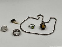 Lot contents including the four rings, shark's tooth pendant, and sterling silver necklace laid flat for detail.