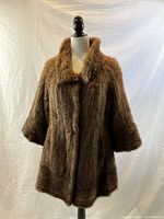 Front view of vintage ladies' brown fur jacket on mannequin showing full length, collar, and sleeves.