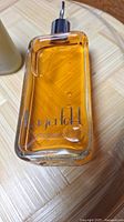 Clear glass rectangular bottle of Lagerfeld after shave lotion containing amber liquid with dispensing pump.