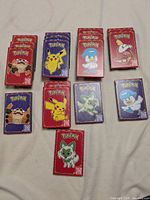 Displays pokémon card packs arranged on a surface, showing the front of assorted packs with different characters.