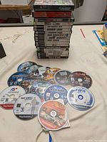 14 disc-only games spread out on cloth, mostly PS2 titles, showcasing Call of Duty, Tony Hawk Proving Ground, Gran Turismo 4, FIFA Soccer, Far Cry, and others