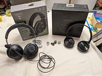Photo showing JBL Quantum 100 gaming headset with detachable mic, two pairs of wireless Jabra earbuds without cases, and wired earbuds along with Turtle Beach Stealth 600 packaging.