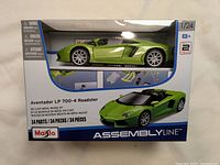Front view of the green Lamborghini Aventador LP 700-4 model in its display box showing Assembly Line branding and specifications.