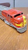 Close-up of Marx O-Gauge Santa Fe Electric Diesel Locomotive #1095 painted red and silver with yellow logo, showing some surface wear.