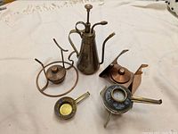 Overview of copper and brass fondue set pieces including burners and fuel dispenser on a white background.