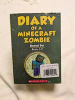 Front of the boxed set showing title 'Diary of a Minecraft Zombie Boxed Set Books 1-9' with sealed shrink-wrap and Scholastic logo.