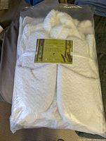 Sealed package of white 3-piece bathrobe set showing folded bathrobe inside clear packaging