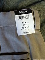 Close-up photo of the Haggar brand tag attached to the khaki dress pants indicating size 32 x 32 and price $59.99.