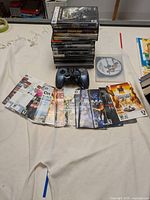 Photo showing stacked PC game cases with blue Logitech F510 controller and laid out game manuals.