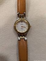 Front view of Royale Pantera wristwatch showing white dial with gold Roman numerals and diamond accent, two-tone case and light brown leather strap.