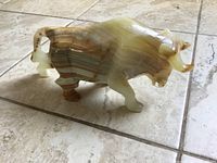 Side view of the bull figurine showing natural stone bands and polished surface.