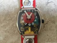 Close-up photo of the watch face showing the teeter totter children figurines inside and the hands indicating time