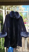 Full front view of dark beaver fur jacket hanging on fence