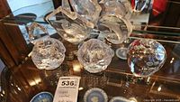 Photo of two crystal snowball candle holders and art glass apple on a glass shelf