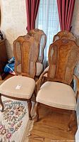 Group photo of four caned wood dining chairs with beige cushioned seats, showing detailed back carving and cane insert work.