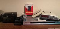 Photo showing Sony DVD player, alarm clock radio with remote, Sony Walkman box, and vintage intercom together on a table.