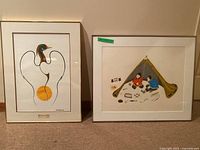 Two framed artworks side by side on floor against wall