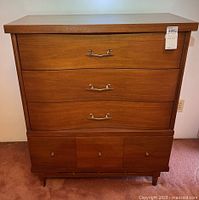 Front view of mid-century modern dresser showing three large curved drawers with metal handles and three smaller bottom drawers with round knobs on caster feet.