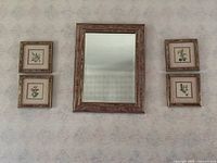 Mirror mounted on wall with 4 framed floral prints surrounding it on 2 sides, showing overall size and style of items.