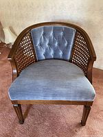 Front view of vintage barrel chair showing curved cane back and gray tufted upholstery on wood frame