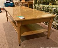 Front left angle view of rectangular coffee table showing wood grain top and four tapered legs