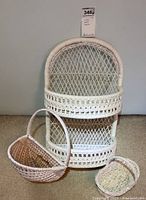 White wicker wall shelf with two tiers and two wicker baskets positioned below, showing full lot contents