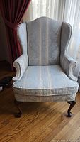 Full front view of wingback chair showing upholstery, arms, and legs