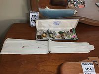 Overall arrangement showing gloves, hat pins, and jewelry box with brooches on a wooden surface.