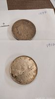 Photo showing both the 1877 silver 5 franc coin and the 1937 Canadian silver dollar coin on white paper with handwritten dates.