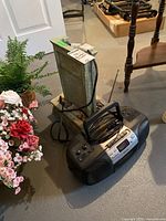 Electric water fountain with vertical stone-like structure, placed next to Aiwa CD radio cassette boom box on floor.