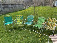 Full set of 5 vintage folding lawn chairs with different woven plastic strap patterns and aluminum frames shown on grass outdoors.