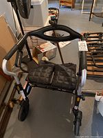 Photo of black rollator walker with padded seat and front wheels, showing structure and handles.