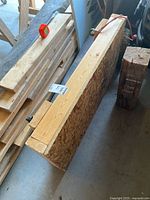 Wood moving dolly leaning against wall in garage, showing particle board top and wood framing with tape measure on top.