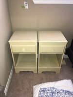 Pair of cream-colored nightstands shown side by side against a wall on carpeted floor.