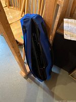 Portable folding hammock cot folded inside blue carry bag, standing upright in storage area.